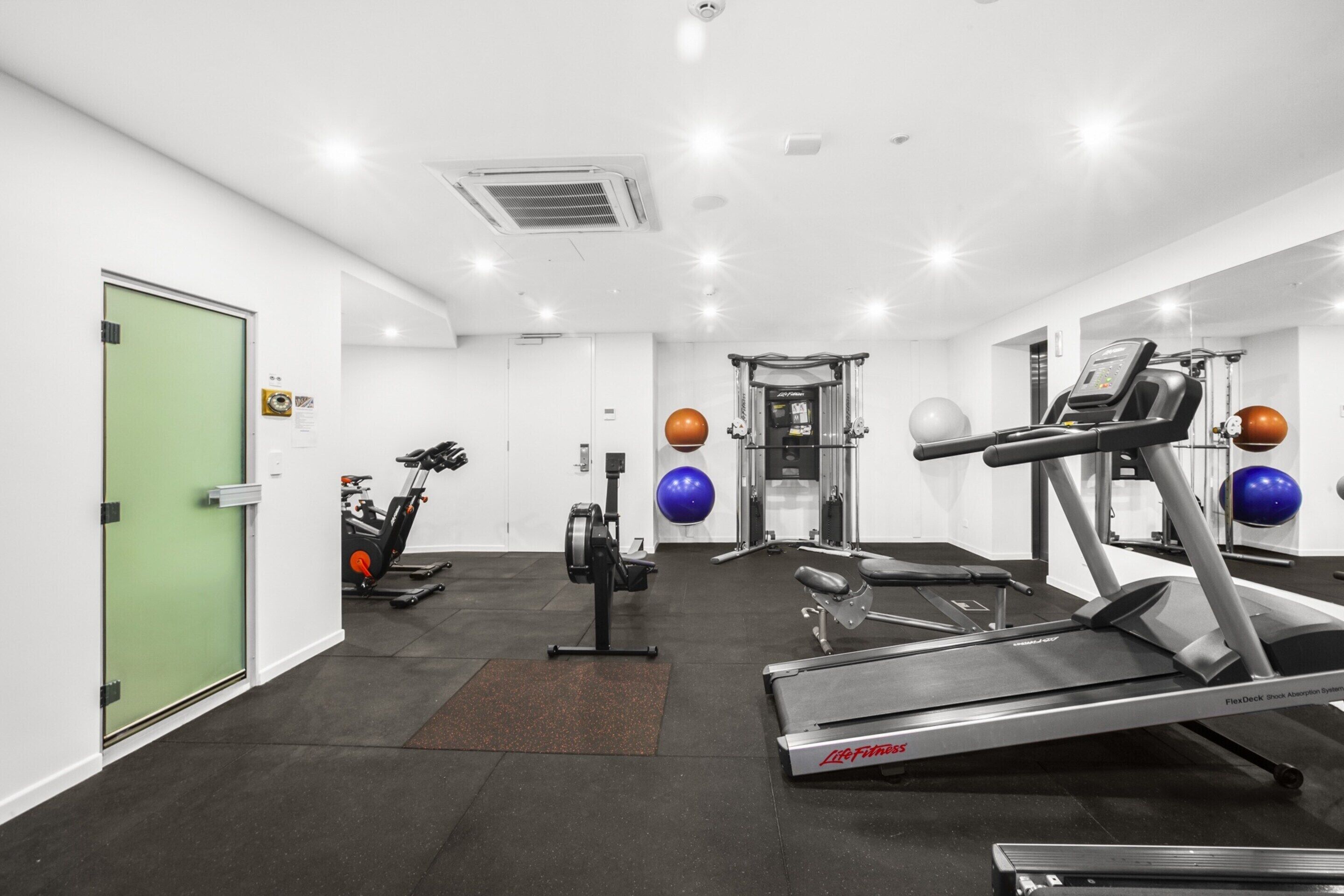 A gym with cardio machines, weightlifting equipment, and exercise balls.