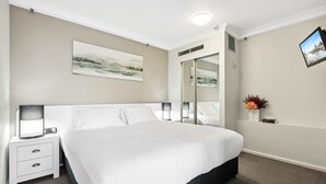 Una camera da letto ordinata con un letto grande, lampade da comodino, un tavolino e uno specchio, con un quadro appeso alla parete.