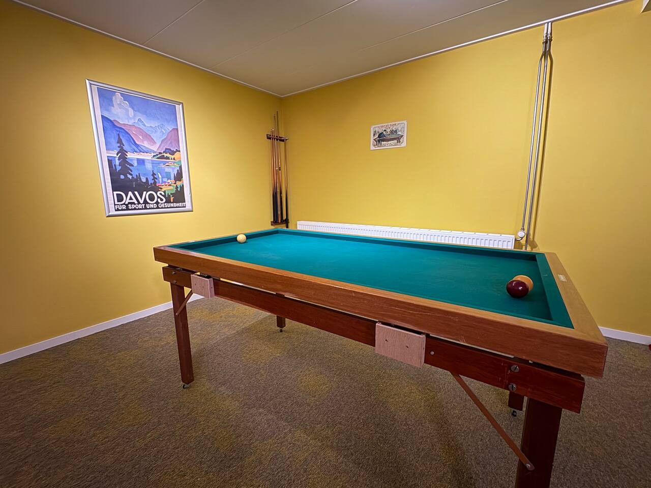 A pool table in a room with yellow walls, a poster on the wall, and a radiator.