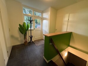 A room with a green accent wall, a wooden counter, a potted plant, and a door with windows.