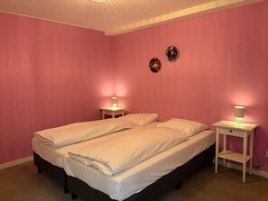 Ein Doppelbett mit weißen Leinen in einem Zimmer mit rosafarbenen Wänden und zwei Nachttischen mit Lampen.