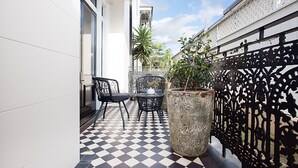 A checkered outdoor patio with a table and chairs, a large planter, and a decorative fence. - Comfortable Renovated Studio Close To City (Sydney)