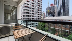 A balcony with a wooden table and chairs, overlooking a cityscape with high-rise buildings and construction sites. - Gorgeous 3-bed Apartment Near Flagstaff Gardens (Melbourne)
