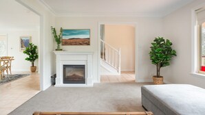 A living room with a fireplace, a staircase, and potted plants. - Stunning Katoomba Home With Lush Garden&playground (Katoomba)