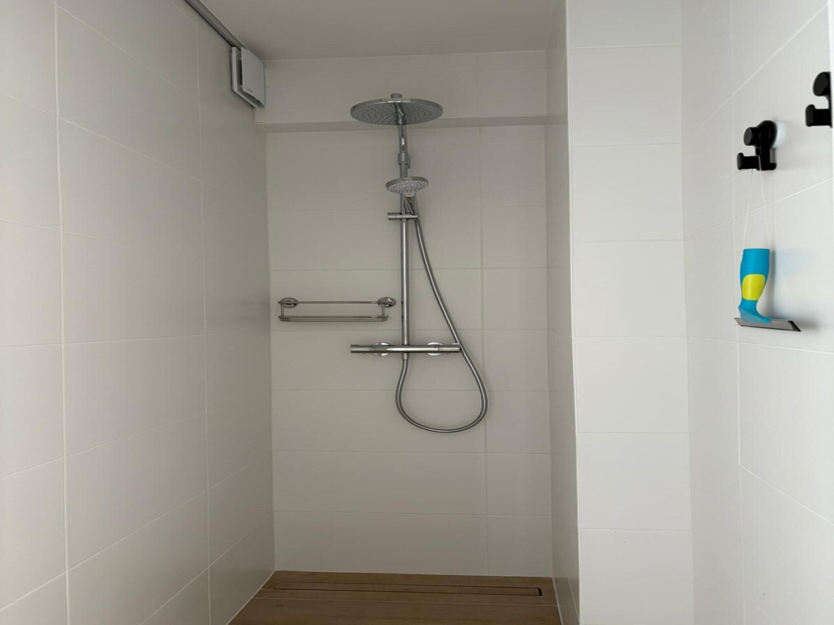 A shower with a handheld showerhead and a wall-mounted faucet.
