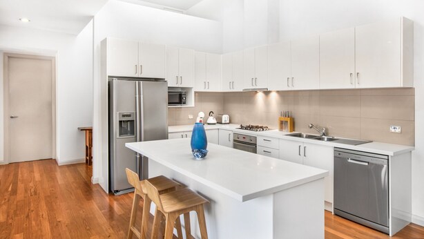 A modern kitchen with white cabinetry, stainless steel appliances, and a central island. - 2-bed Apartment With Parking & Balcony Near Trains (Melbourne)