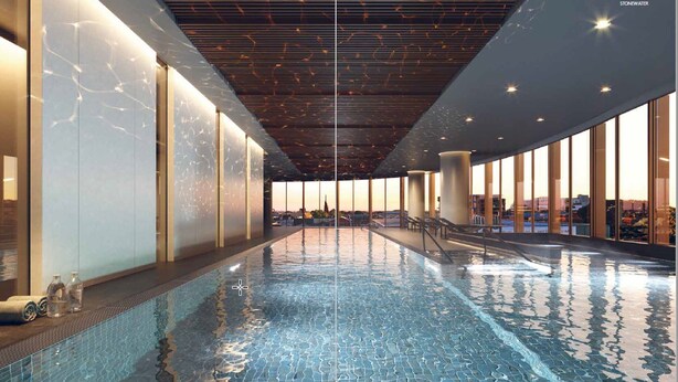 A modern indoor swimming pool with a clear view of the cityscape through large windows.