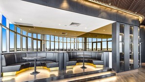 A modern interior with a curved seating area, a central round table, and large windows offering a view.