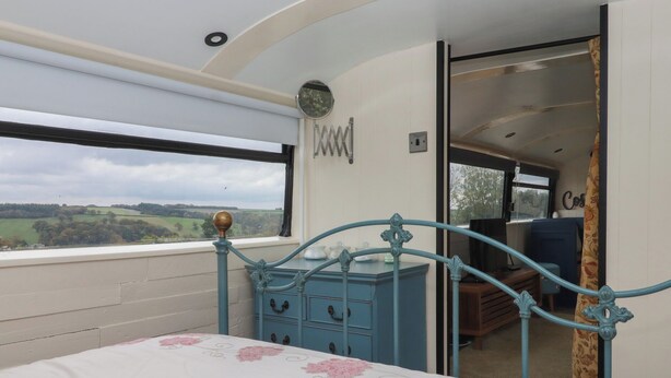 A bedroom with a bed, a dresser, and a view of the countryside.