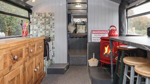 A cozy interior with a wooden cabinet, a red kettle, and a warning sign. - The Bus on the Hill (Tiverton)