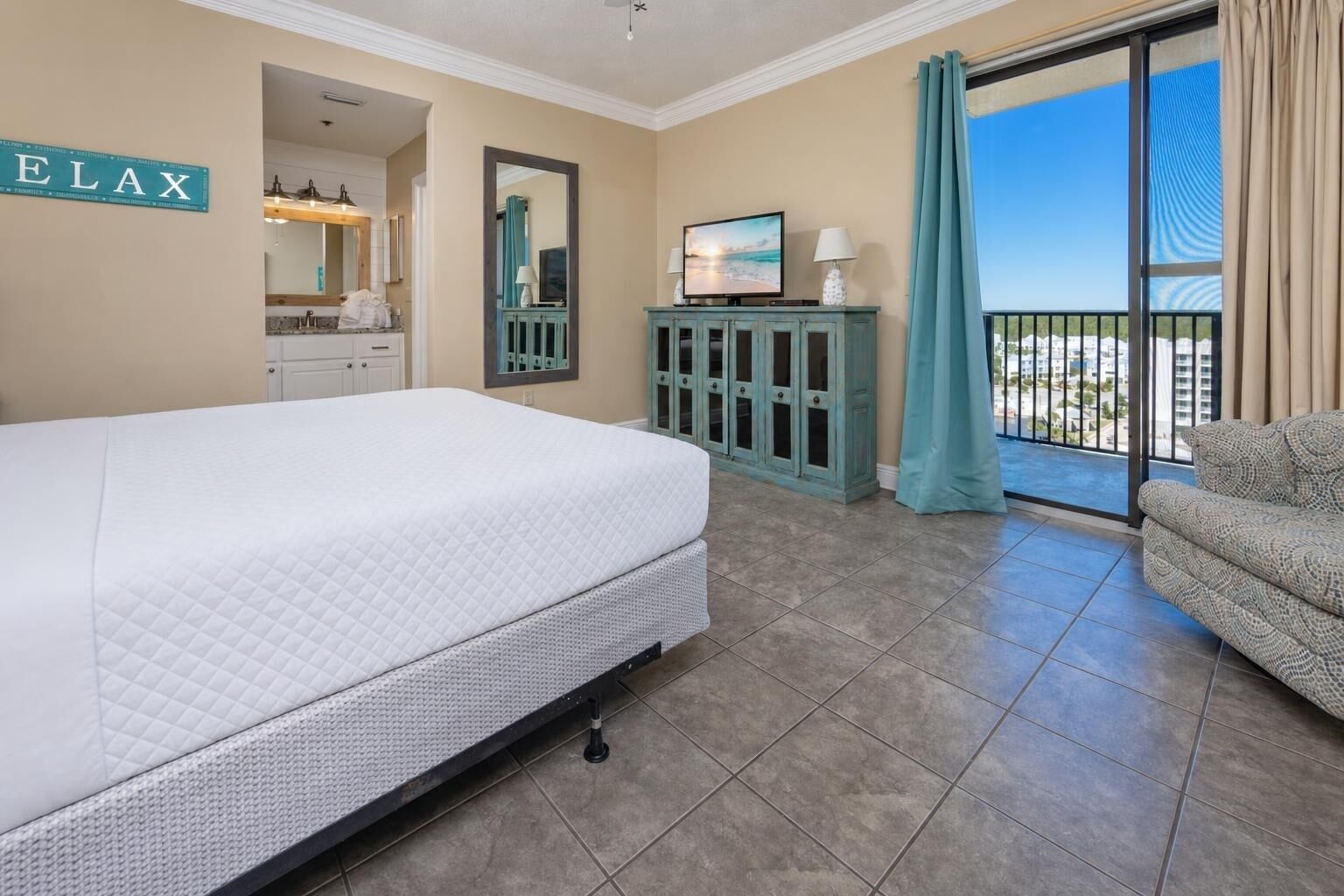 Une chambre d’hôtel avec un lit, une télévision, une armoire, un balcon avec vue et un panneau sur le mur.