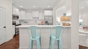 A modern kitchen with white cabinetry, stainless steel appliances, and teal chairs at the island. - Pool | Pet Friendly | Clean & Bright | Patio | Grill | Great Kitchen | Beach Chairs (St. Simons Island)