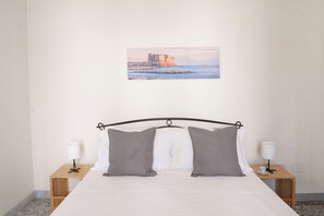 A neatly arranged bedroom with a bed, two bedside tables, and a wall-mounted picture of a coastal scene. - A Casa di Antonio by Wonderful Italy (Naples)
