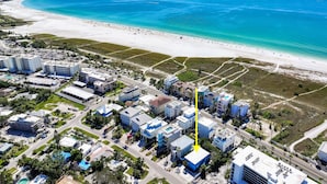 Vista aérea de un pueblo costero con playa, edificios y carreteras.
