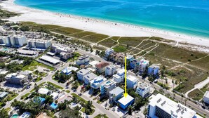 Luftaufnahme einer Küstenstadt mit Strand, Gebäuden und Straßen.