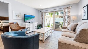 Ein modernes Wohnzimmer mit Sofa, Couchtisch, Fernseher und einem Essbereich mit Tisch und Stühlen.