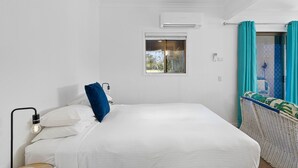 A bedroom with a bed, a bedside lamp, a window, and a view of the outdoors. - The Little Blue Shack - Marcoola Granny Flat (Sunshine Coast)