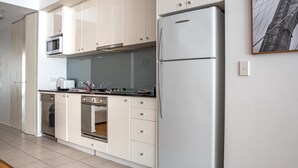 A modern kitchen with white cabinets, a stainless steel refrigerator, a microwave, and a stove. - Stylish Studio With Pool & Gym in Heart of Sydney (Sydney)