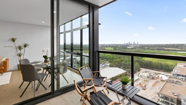 A modern balcony with a city view, furnished with chairs and a table, and potted plants. - Chic 1-bed With Pool by River, Ferry & Amenities (Sydney)