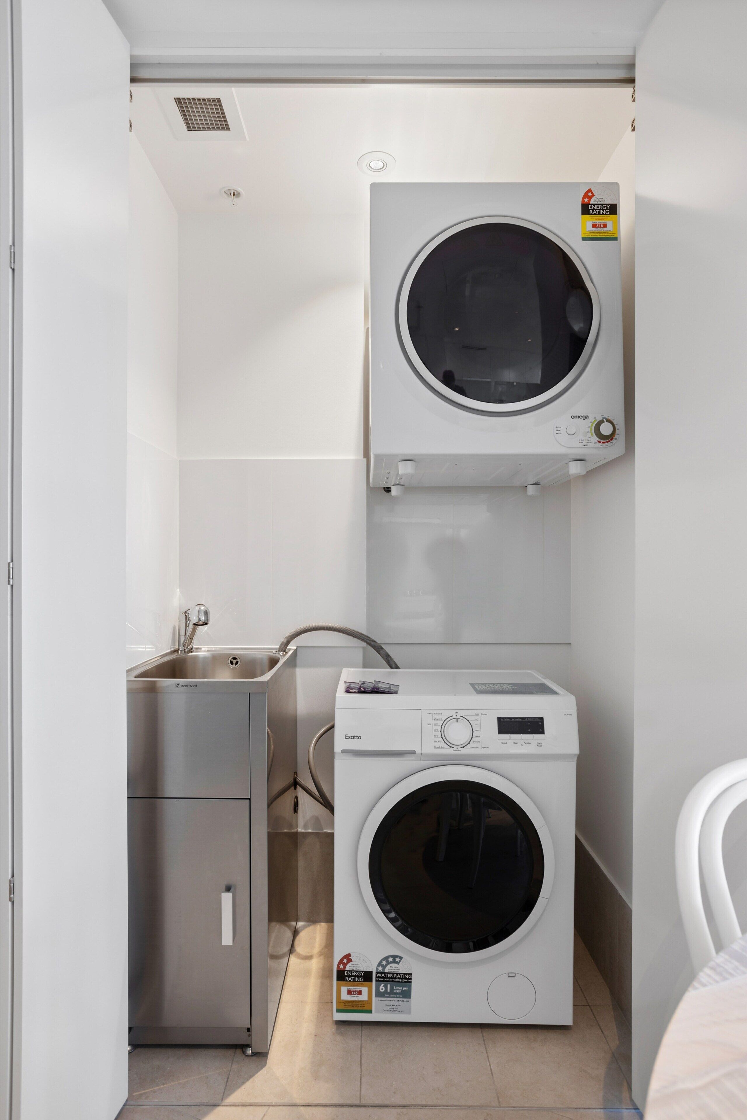 A compact laundry room with a washing machine, a dryer, and a small sink.