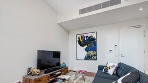A modern living room with a flat-screen TV, wooden entertainment unit, and a glass coffee table. - Inner-city Apartment Minutes Walk to Dining Hubs (Sydney)