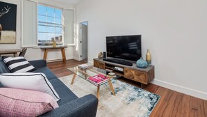 A modern living room with a sofa, coffee table, and a flat-screen TV. - Inner-city Apartment Minutes Walk to Dining Hubs (Sydney)