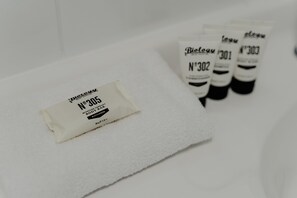 Une serviette blanche avec une étiquette, et plusieurs flacons de lotion en arrière-plan.
