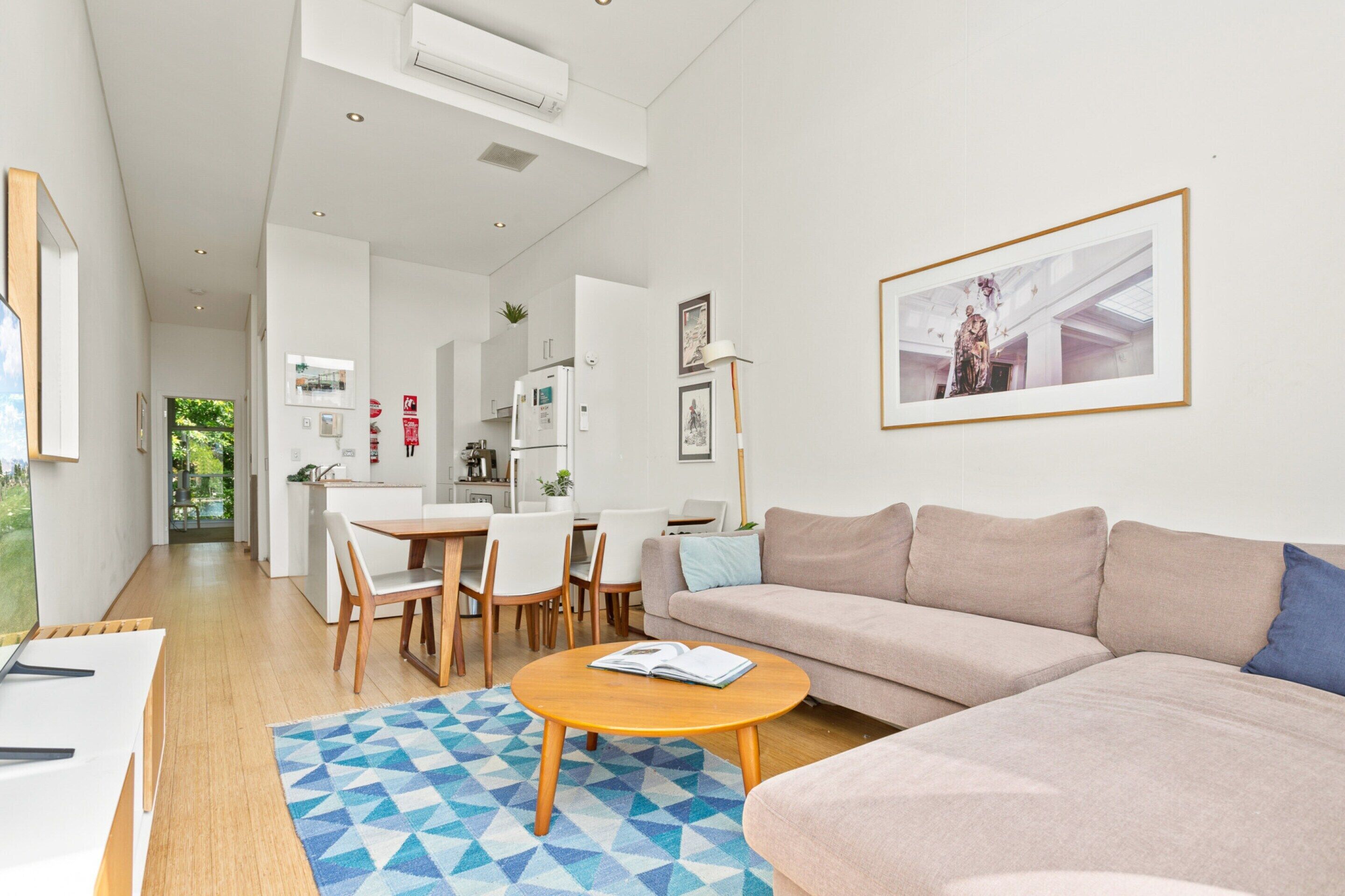 A modern living room with a sofa, coffee table, and dining area.