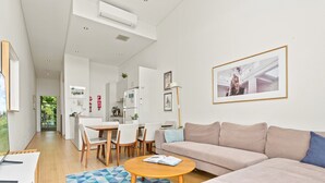 A modern living room with a sofa, coffee table, and dining area. - Charming Modern Apartment With City Views (Sydney)