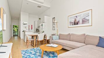 A modern living room with a sofa, coffee table, and dining area.