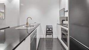 Eine moderne Küche mit einem Edelstahl-Kühlschrank, einem eingebauten Ofen und einem Spülbecken mit goldenem Wasserhahn.