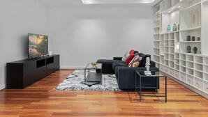 Ein modernes Wohnzimmer mit einem schwarzen Sofa, einem Glastisch und einer weißen Regaleinrichtung an der Wand.