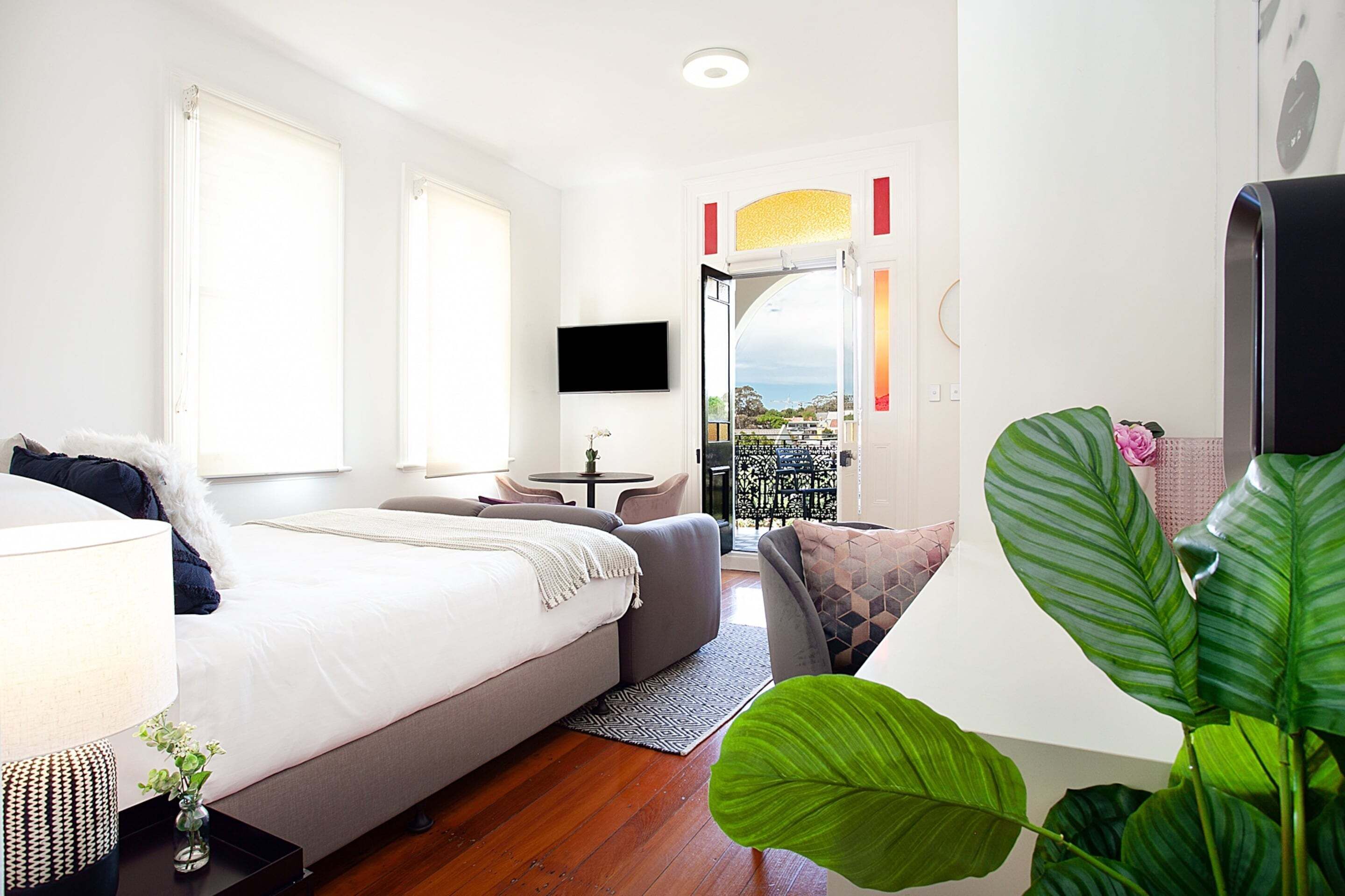 Una habitación de hotel moderna con una cama, un sofá, un televisor y un balcón con vistas.