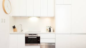 A modern kitchen with white cabinets, stainless steel appliances, and a clock on the wall. - Charming Studio With Balcony in Inner-city Glebe (Sydney)