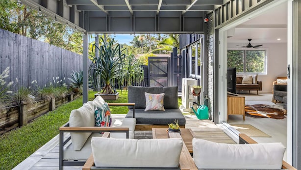 A modern outdoor living area with a sofa, chairs, and a dining table. - Trendy 2-bed Home With Outdoor Entertainment (Sunshine Coast)