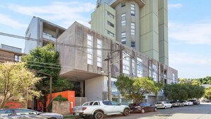 Un bâtiment moderne doté d’une conception architecturale originale, caractérisé par une section cylindrique imposante et une façade plate.