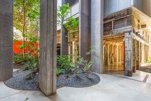 A modern building with concrete pillars, a garden area with small trees, and a wooden staircase leading to an upper level. - Chic 1-bed Apartment in the Heart of Newtown (Sydney)