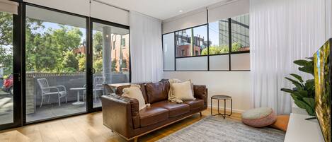 Una sala de estar moderna con un sofá de cuero, una mesa de centro y un ventanal con vistas al exterior.