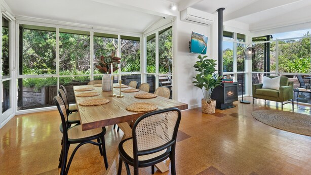 A spacious dining area with a large wooden table, woven placemats, and black chairs. - Spacious Coastal 4-bed Steps From the Sand (Melbourne)