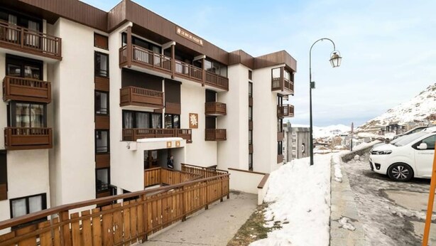 A multi-story building with balconies, a snow-covered ground, and a parked car. - VAL Thorens Rental: Studio for 4 on the Edge of the Slopes (Les Belleville)