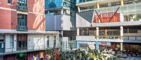 A courtyard with outdoor seating, surrounded by modern buildings with various shops and restaurants.