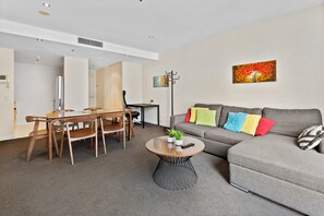 A modern living room with a grey sofa, a wooden dining table, and a round coffee table with a plant.