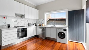 A modern kitchen with white cabinets, a built-in oven, microwave, and dishwasher. - Huge Harbour View Apartment In Historic Home (Sydney)