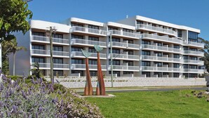 Un hotel de varios pisos con balcones, un área de estacionamiento y un letrero que dice 'OHANA'.