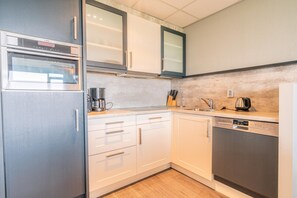 Una cocina compacta con horno integrado, cafetera y lavavajillas.