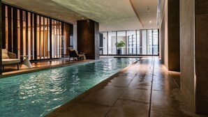 An indoor swimming pool with a modern design, including a tiled floor and a seating area with a sofa and chairs. - 2-bed With Harbour Views & Outstanding Amenities (Melbourne)