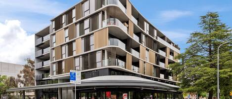 A multi-story building with a curved facade, balconies, and a covered entrance area.