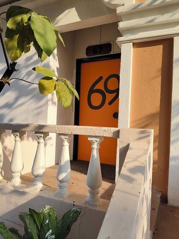 A balcony with white balustrades and a number '69' sign on a wall.