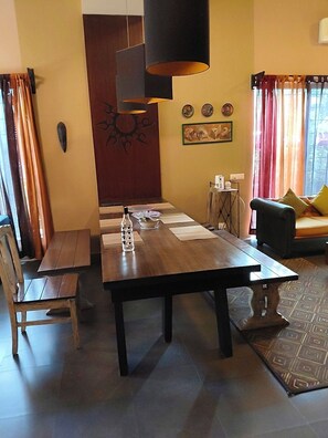 A dining area with a wooden table, chairs, and a modern pendant light.