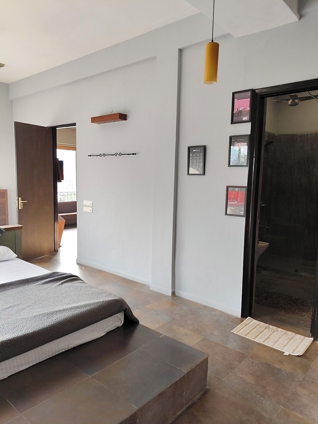 Une chambre d’hôtel moderne comprenant un lit, un banc en bois, une petite table, une porte et un porte-serviettes fixé au mur.
